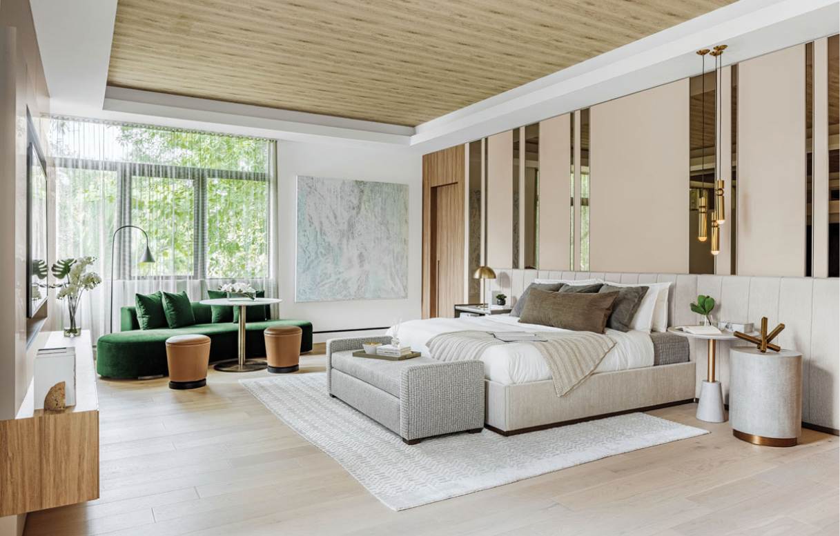 A spacious, modern bedroom featuring a large bed with a padded headboard, adorned with neutral bedding and accent pillows.